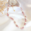 Close-up of a handcrafted choker necklace featuring natural Strawberry Quartz crystals and white freshwater pearls, with an 18K gold-plated adjustable clasp.